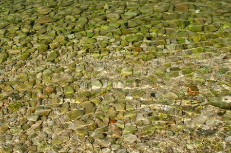 The background of pebble stones throught emerald water, Nemira, Croatia