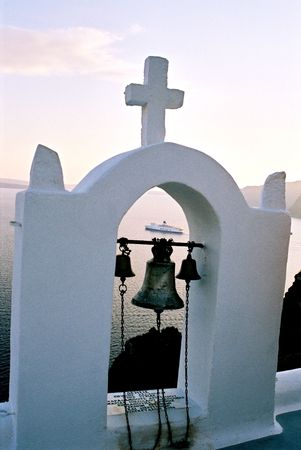 Small belltower of a chapel on high seacoast, Santorini, Greece, winter eveningの写真素材