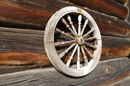 Wheel on a timbered wall. This wheel  is the part of a distaff - the old tool for hands made a  fabricsの写真素材