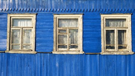 Three white windows in the old blue wooden wall, traditional Russian village houseの写真素材