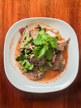 Cooked liver in spicy condiment in white plate on wood tableの写真素材
