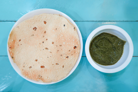 Appalam or Papadam brad, Indian snack with green sauce on blue wood backgroundの写真素材