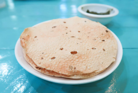 Appalam or Papadam brad, Indian snack with green sauce on blue wood background