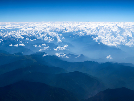 Clouds and snow over the mountains view from the airplaneの写真素材