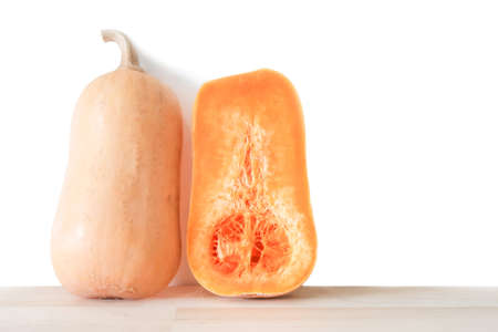 Raw butternut squash pumpkin vegetable or Butternut Pumpkin cut on wood board and white background, right copy spaceの写真素材
