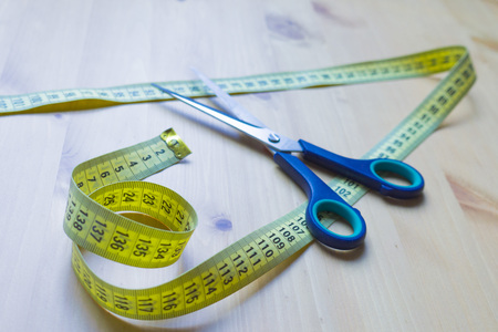 Scissors and centimeter on a wooden tableの写真素材
