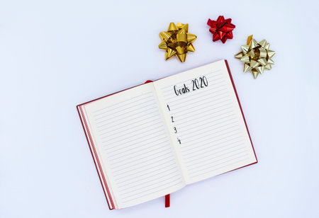 Christmas and New Year 2020 goals. Notebook with wishes on a white background. Flat lay, top view.
