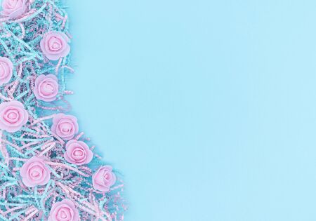 Pink roses on blue background. Copyspace for your text. Flatlay, top view. Romantic concept. Pink flowers lie on shredded paper.の写真素材