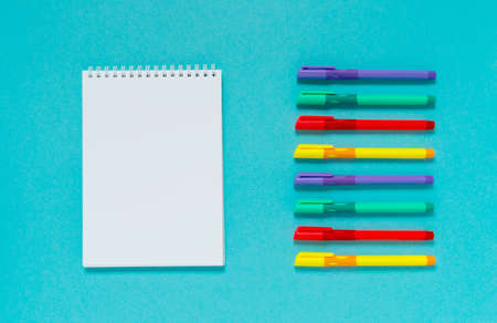 Open blank spiral notepad with multicolored pens on a blue background. Flat lay, top view, copy space.の写真素材
