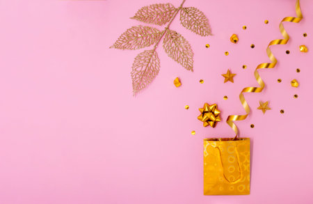 Golden confetti with gift bag and ribbon on pinkの写真素材
