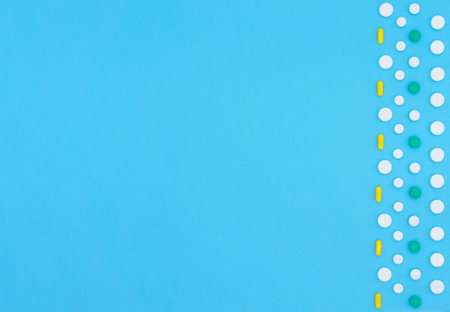Multicolored pills, tablets and capsules of pharmaceutical medicine on a blue background. Copy...