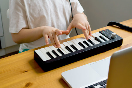 Childrens hands learn to play a musical instrument online. Distance learning to play the piano....