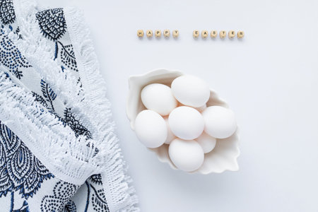 White eggs in a white dish with a beautiful tablecloth on a light background. Happy Easter...