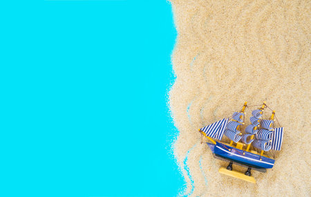 Sand frame with a miniature ship on a blue background. Flat lay. Top view. Copy space. Vacation and...