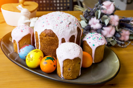 Traditional Easter cake with colored eggs on a platter on a wooden table