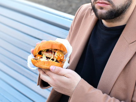 burger with 2 cutlets holding a man with beardの写真素材