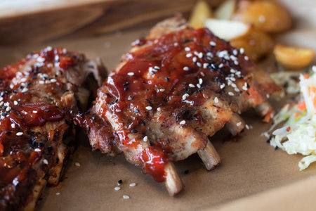Grilled and smoked ribs with bbq sause with potatoes and coleslaw salad close up black white sesameの写真素材