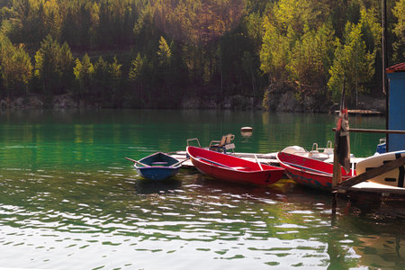 landscape with marble lake, pier with old wooden fishing boat boats, summer or autumn viewの写真素材