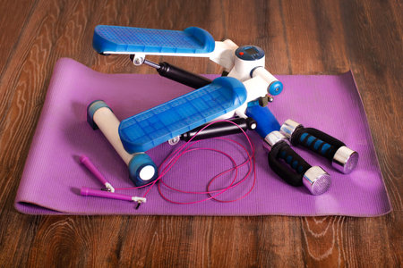 Home fitness. Stepper, dumbbells, jump rope, yoga mat. at home background