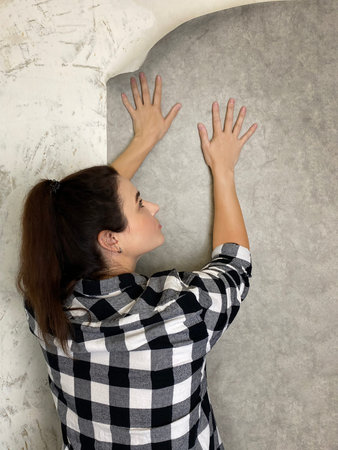 Woman putting up gray wallpaper