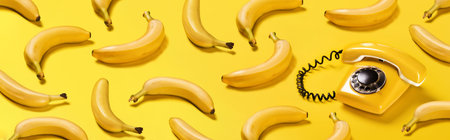 Banner bananas and old yellow phone with hard shadows pattern on yellow background flat lay bananaphoneの写真素材