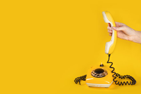 Banner with old yellow phone, hand picks up the phone on yellow background flat lay copy space for you textの写真素材