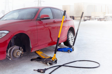 Tire fitting on the street. Jack red car photoの写真素材