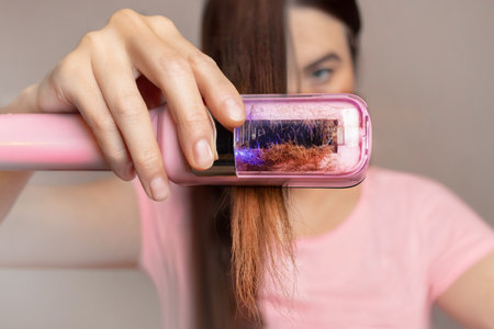 A woman uses a machine to cut the split ends of her hair. Close upの写真素材