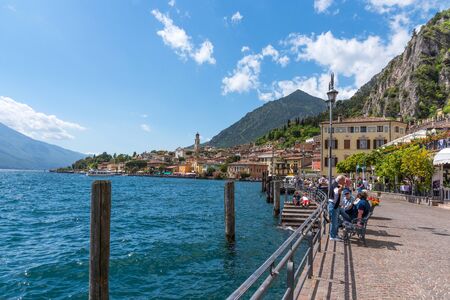 Limone sul Garda, Italy - April 30,2018: Picturesque view of Limone sul Garda, Lake Garda, Italy. Beautiful spring day. Colorful flowers decorating old houses, boats with tourists and restaurants.のeditorial素材