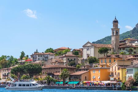 Limone sul Garda, Italy - April 30,2018: Picturesque view of Limone sul Garda, Lake Garda, Italy. Beautiful spring day. Colorful flowers decorating old houses, boats with tourists and restaurants.のeditorial素材