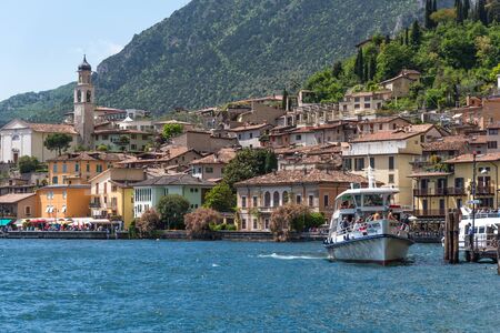 Limone sul Garda, Italy - April 30,2018: Picturesque view of Limone sul Garda, Lake Garda, Italy. Beautiful spring day. Colorful flowers decorating old houses, boats with tourists and restaurants.のeditorial素材