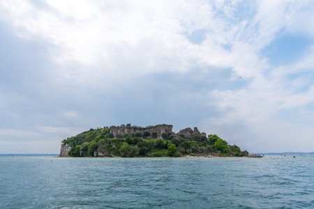 Sirmione, Italy - April 29, 2018: Amazing panoramic view of Grotte di Catullo from the Garda Lake. The ruins of a Roman villa and Stony Beach. Ancient Roman archaeological site in Sirmione.のeditorial素材