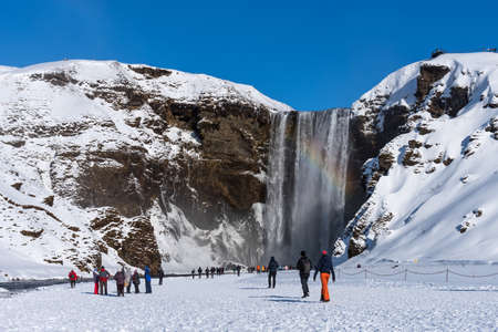Skogafoss, Iceland - March 5, 2020: Tourists at Skogafoss Waterfall, one of the biggest waterfalls and most popular tourist attractions in Iceland.のeditorial素材
