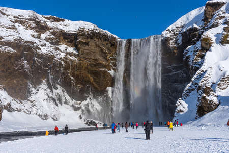 Skogafoss, Iceland - March 5, 2020: Tourists at Skogafoss Waterfall, one of the biggest waterfalls and most popular tourist attractions in Iceland.のeditorial素材