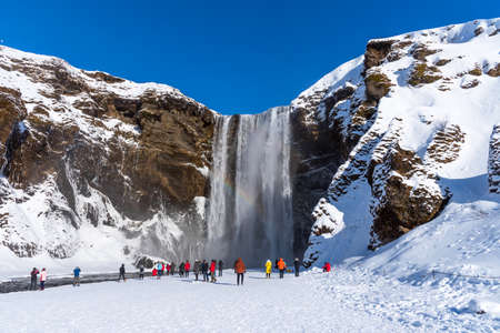 Skogafoss, Iceland - March 5, 2020: Tourists at Skogafoss Waterfall, one of the biggest waterfalls and most popular tourist attractions in Iceland.のeditorial素材