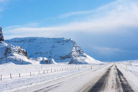 Empty asphalt road on background of snowy landscape in Iceland in winter. Highway road with snow and blue clear sky in Iceland.の写真素材