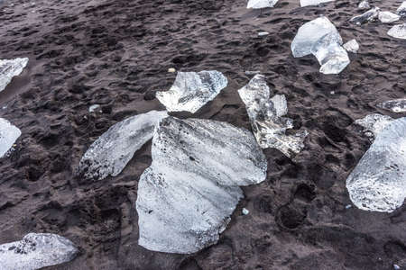 Amazing picturesque view of black sand beach with iceberg pieces on Diamond beach near Jokulsarlon lagoon in winter time, Iceland.の写真素材