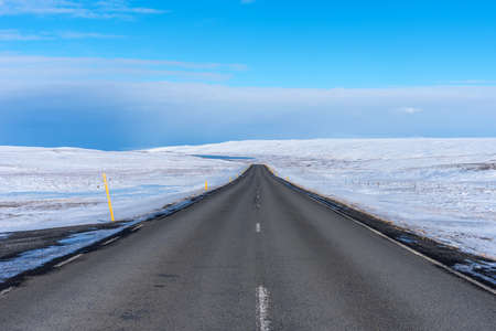 Empty asphalt road on background of snowy landscape in Iceland in winter. Highway road through Iceland landscape at sunny day.の写真素材