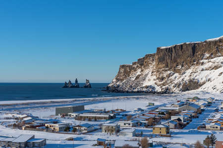 Aereal winter landscape view of village Vik in Iceland. The beautiful town on the main ring road around Iceland. Background of beach with black sand and Reynisdrangar in winter.の写真素材