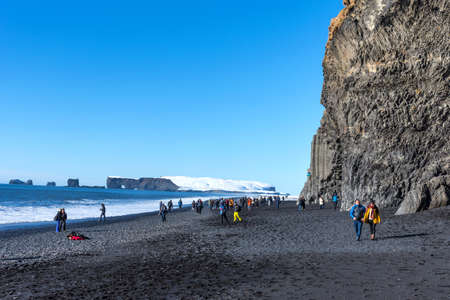 Vik, Iceland - March 6, 2020: Black sand beach of Reynisfjara in Iceland. Tourists on the famous black sand beach with columns of black basalt Reynisfjara on the south coast of Iceland.のeditorial素材