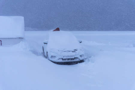 Car under the snow during heavy snowfall. Heavy snowfall and snow-covered car in a snowdrift.の写真素材