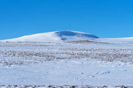 Beautiful winter landscape with mountains covered snow, cold frosty weather and asphalt road through a white field in Iceland.の写真素材