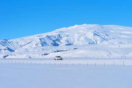 Route 1, Iceland - 5 2020: Beautiful winter landscape with mountains covered snow, cold frosty weather and asphalt road through a white field with cars in Iceland.のeditorial素材