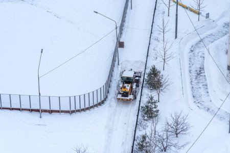 Moscow, Russia - February 14, 2021: The tractor cleans snow on the road after a heavy snowfall. A...