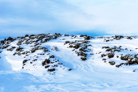 Typical Icelandic winter landscape with picturesque blue sky. Beautiful winter landscape with mountains covered snow, cold frosty weather and white field in Iceland.の写真素材