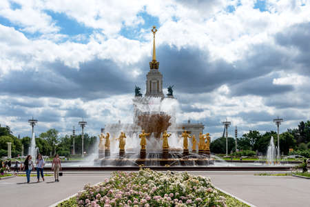 Moscow, Russia - June 30, 2021: Panoramic view of The Friendship of Nations fountain and the main entrance to VDNKh with people walking along the main alley in Moscow, Russia.のeditorial素材