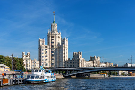 Moscow, Russia - August 12, 2022: Panoramic view of the Kotelnicheskaya Embankment Building, Bolshoi Ustyinsky bridge and tourist boat on Moskva River in summer.のeditorial素材