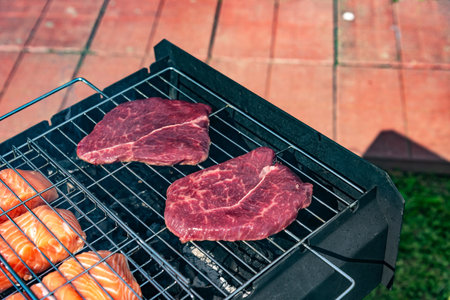 Steak and salmon on barbecue grill in summer. Steak and salmon on the grill.の写真素材