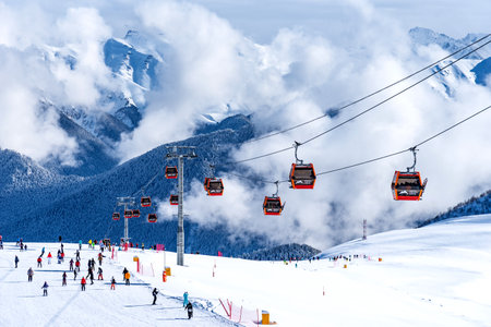 Arkhyz, Russian Federation - January 23, 2024: Tourists ski and snowboard at the Arkhyz resort. Ski lifts in the Arkhyz resort on a sunny day in winter.のeditorial素材