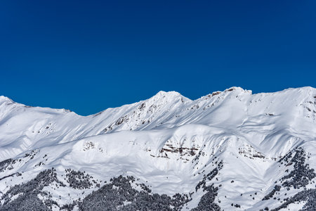 Picturesque winter landscape with mountains, snow, and forest on a sunny day. Caucasus Mountains, Russia.の写真素材